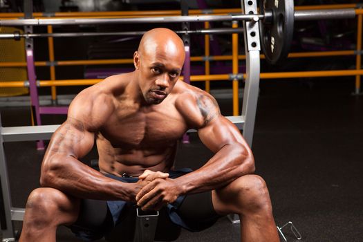 Weight lifter sitting at the bench press about to lift a barbell.