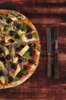Rustic pizza background with copy space. Delicious pizza on dark wooden background, top view.