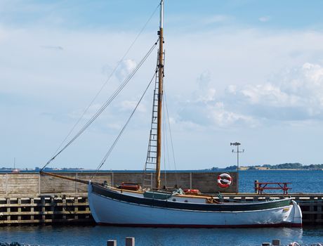 Old vintage traditional wooden sail boat in a small port marina Denmark