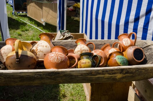 painted clay jugs lying in wooden trough at village market