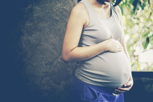 Image of pregnant woman touching her belly with hands