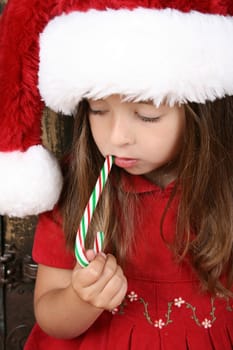 Beautiful brunette christmas girl eating a candy cane 