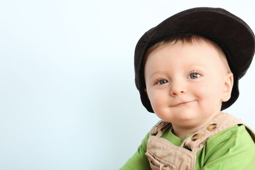 Little boy wearing a hat against blue background