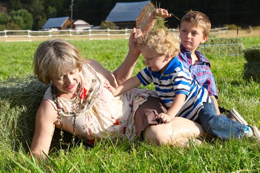 Grandmother playing in the hayfield with her grandsons