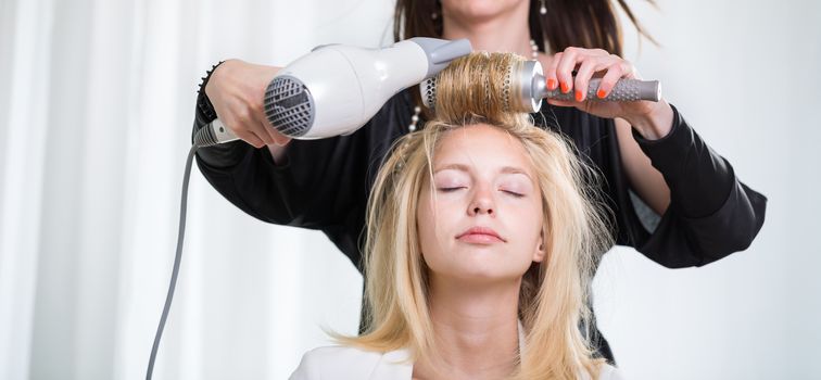 Pretty, young woman having her hair done by a professional hairstylist