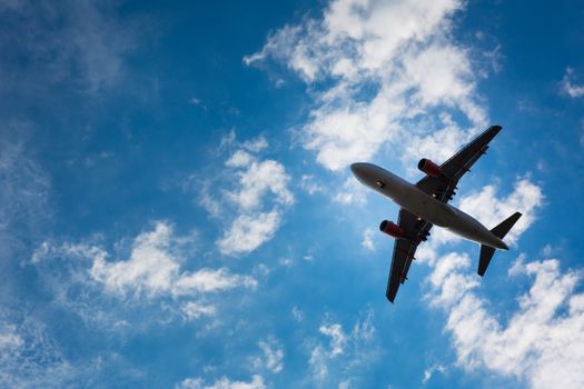 Dark silhouette of an airplane flying over the blue skies