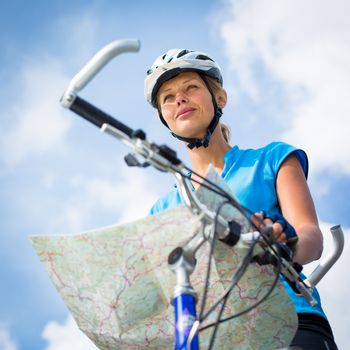 Female cyclist, reading a map, finding her way