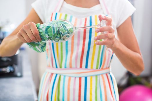 Young woman polishing a glass in her modern kitchen