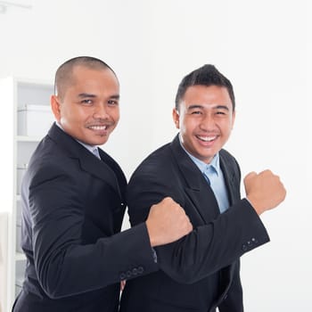 Southeast Asian business men celebrating success in office.