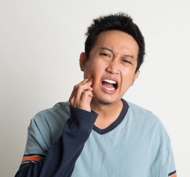 Asian male toothache with painful expression, on plain background. 