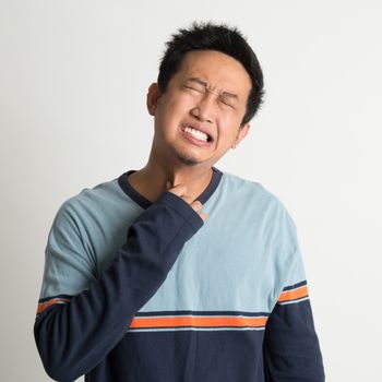 Asian man sore throat with painful face expression, on plain background