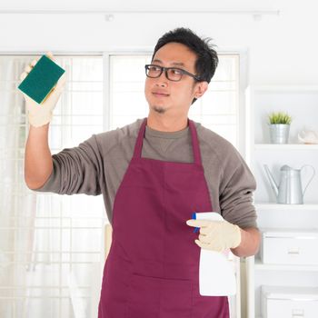 Asian guy housekeeping. House husband doing house chores, with home interiors. Male model.