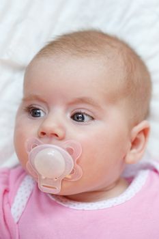 Face of adorable baby with pacifier in mouth 