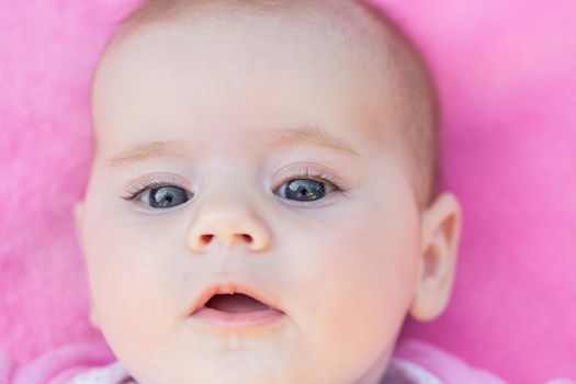 close up of adorable baby face in pink back ground