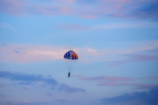 silhouette of unidentified skydiver parachutist on blue sky on sunset