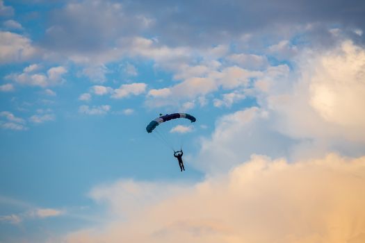 silhouette of unidentified skydiver parachutist on blue sky on sunset
