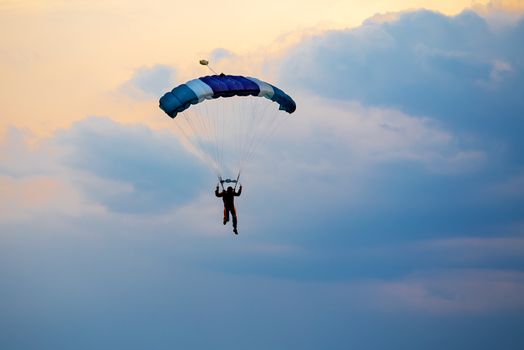 silhouette of unidentified skydiver parachutist on blue sky on sunset