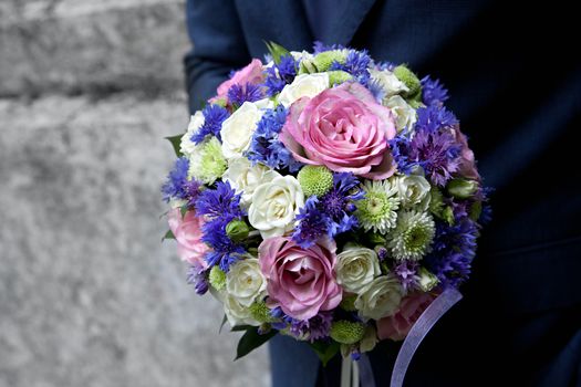 groom holding a bouquet in the hands