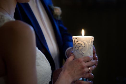 bride and groom holding a candle in church