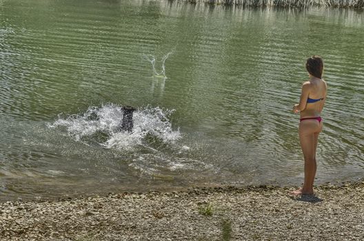 Girsl playiang on the river with their dog