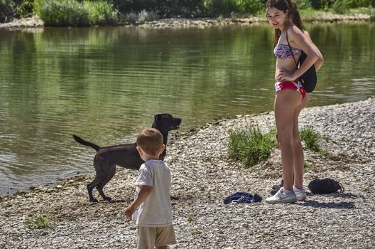Girsl playiang on the river with their dog