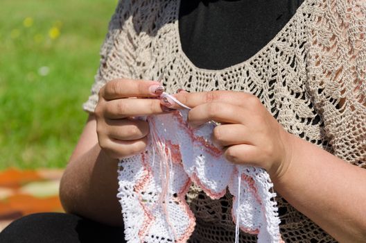 woman knits knitting needles rare knitted fabrics in white thread.