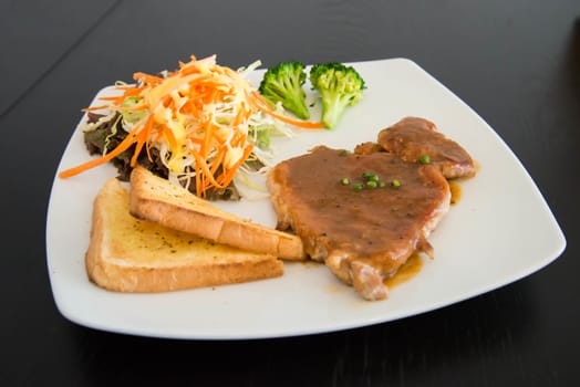Pork steak with toast on a wooden table.