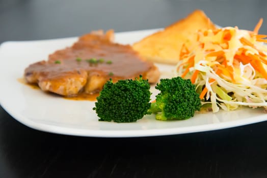 Pork steak with toast on a wooden table.