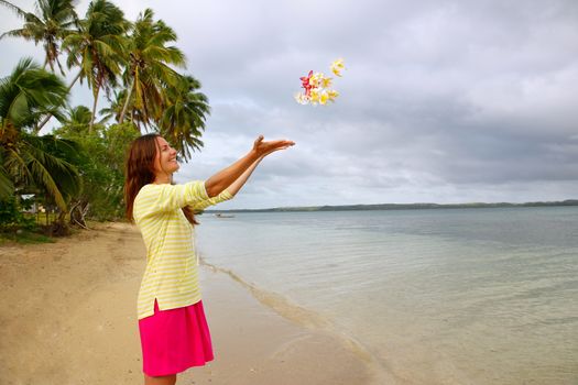 Young woman on a beach throwing flowers in the air, Ofu island, Tonga