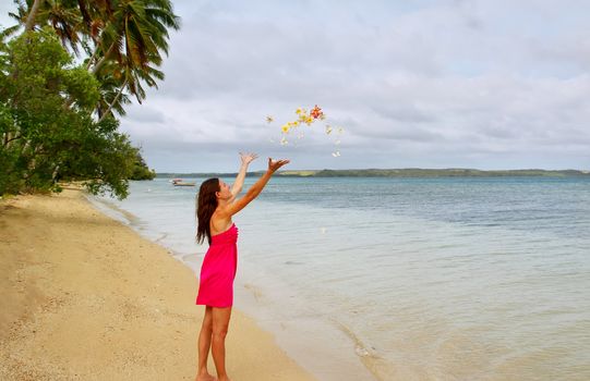Young woman on a beach throwing flowers in the air, Ofu island, Tonga