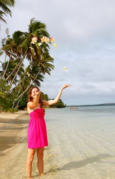 Young woman on a beach throwing flowers in the air, Ofu island, Tonga