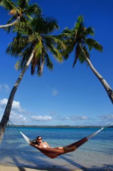 Young woman in bikini laying in a hammock between palm trees, Ofu island, Vavau group, Tonga