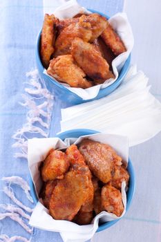 Buffalo chicken wings in bowls on blue tablecloth.