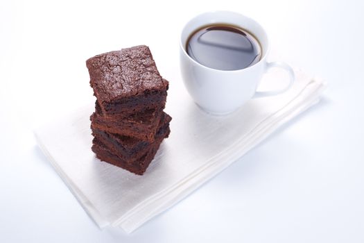 Chocolate brownies on white plate and cup of coffee