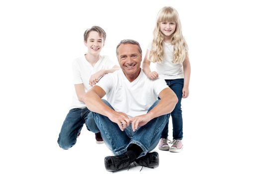 Happy father posing to the camera with his son and daughter