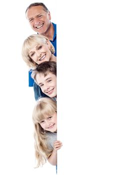 Smiling family posing from behind blank whiteboard