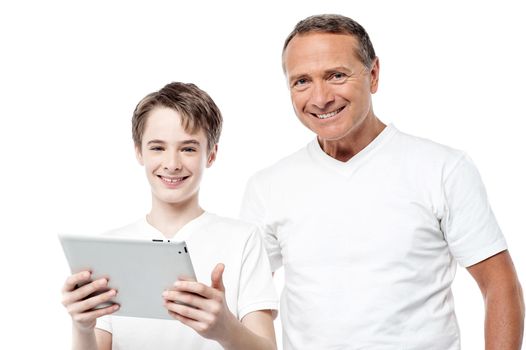 Father and son posing to camera holding tablet pc over white