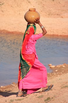 Local woman carrying jar with water on her head, Khichan village, Rajasthan, India