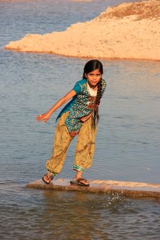 Local girl playing near water reservoir, Khichan village, Rajasthan, India