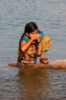 Local girl drinking from water reservoir, Khichan village, Rajasthan, India