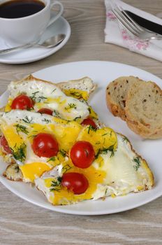 Scrambled eggs with cherry tomatoes, sliced baguette and a cup of coffee

