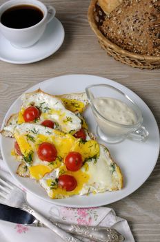 Scrambled eggs with cherry tomatoes, sliced baguette and a cup of coffee

