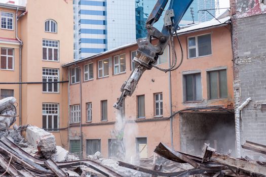 Demolition truck in action. Heap of rubble and a demolished building in the background