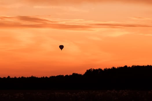 Hot air balloon flying at orange sunset sky