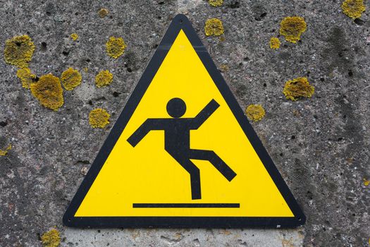 Sign beware slippy on concrete wall