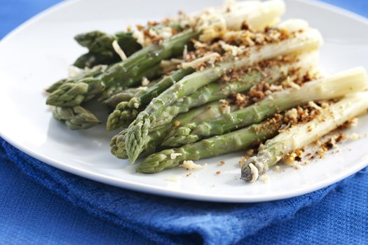 Asparagus gratin on white plate on blue background