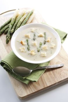 Bowl of asparagus soup with croutons on white background 