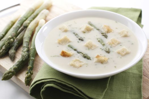 Bowl of asparagus soup with croutons on white background 