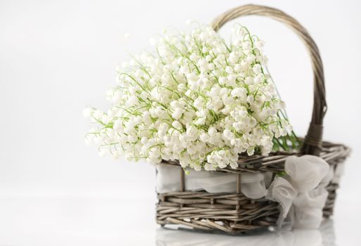 Basket with lilies of the valley on white background 