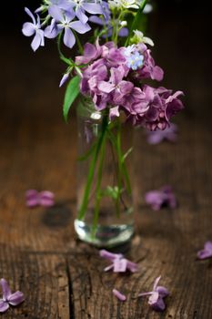 Beautiful spring flowers in a vase on wooden background